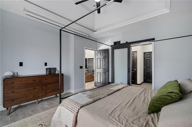 bedroom featuring a ceiling fan, light wood finished floors, baseboards, and a barn door