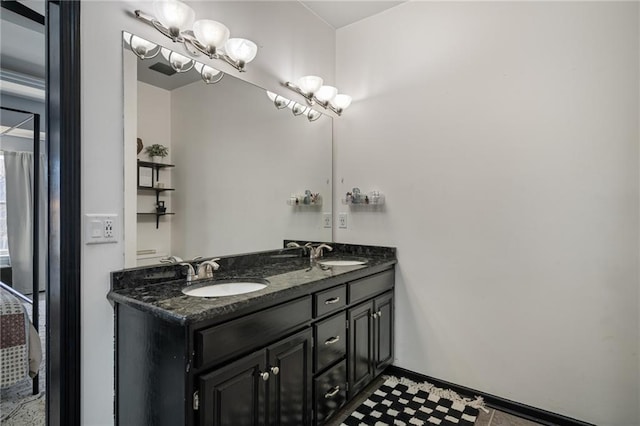 bathroom with double vanity, a notable chandelier, baseboards, and a sink