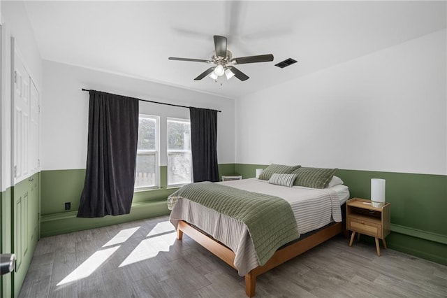 bedroom with a ceiling fan, visible vents, and wood finished floors