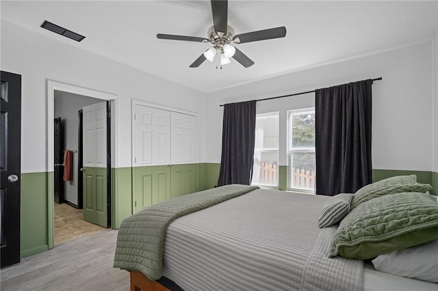 bedroom with ceiling fan, light wood finished floors, and a closet