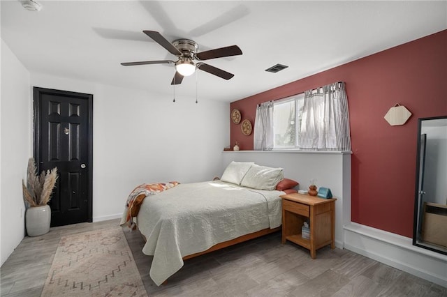 bedroom featuring a ceiling fan, baseboards, visible vents, and wood finished floors