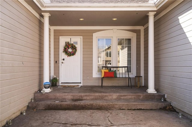 view of exterior entry with covered porch and roof with shingles