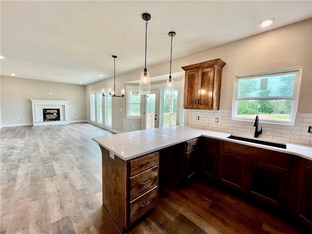 kitchen featuring kitchen peninsula, tasteful backsplash, sink, an inviting chandelier, and dark hardwood / wood-style floors