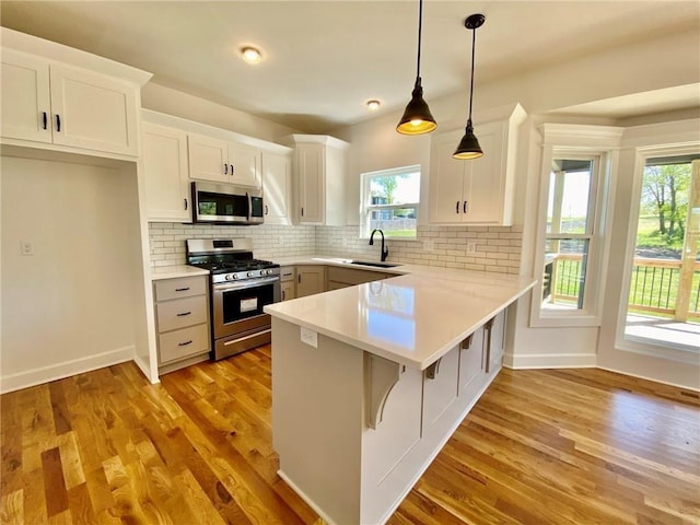 kitchen with white cabinets, a healthy amount of sunlight, stainless steel appliances, and hanging light fixtures