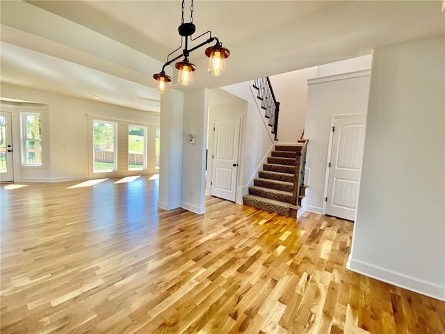 unfurnished living room with light wood-type flooring and a notable chandelier