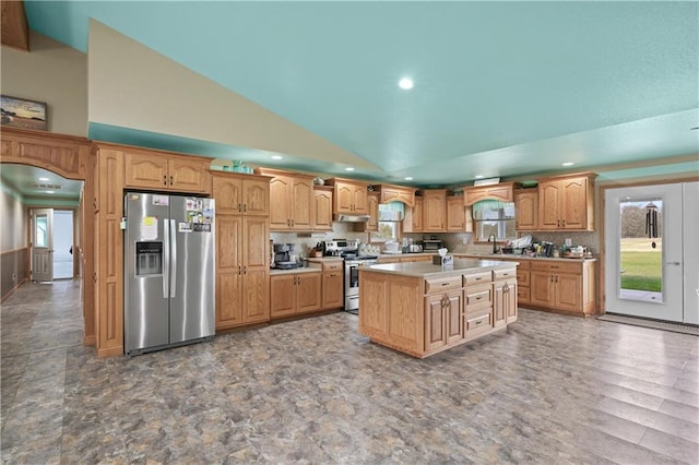 kitchen with stainless steel appliances, sink, tasteful backsplash, high vaulted ceiling, and a center island