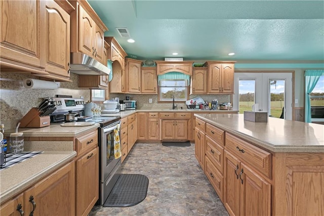 kitchen featuring tasteful backsplash, french doors, stainless steel range with electric stovetop, sink, and a center island