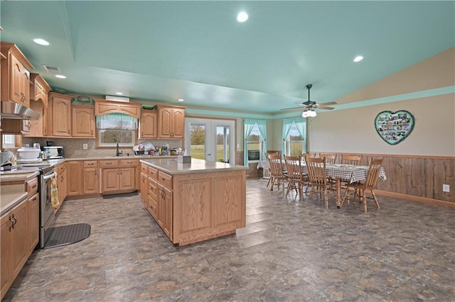 kitchen featuring sink, ceiling fan, a center island, wooden walls, and electric stove