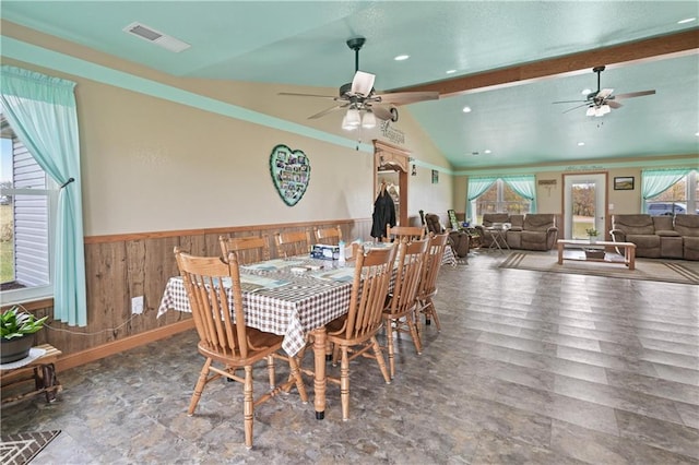 dining area featuring ceiling fan, wooden walls, hardwood / wood-style floors, and vaulted ceiling with beams