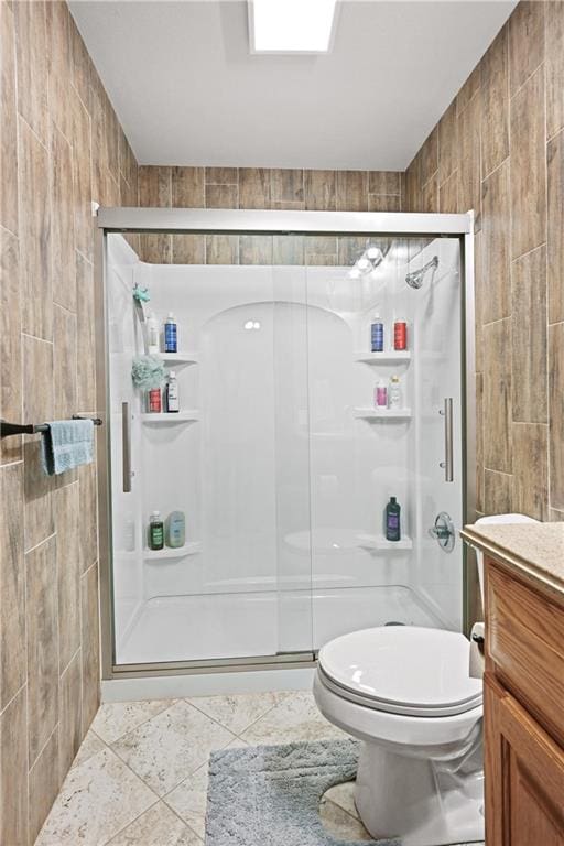 bathroom featuring walk in shower, tile patterned floors, toilet, and tile walls