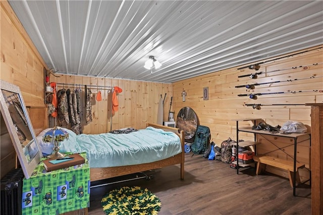 bedroom featuring wooden walls and dark hardwood / wood-style floors