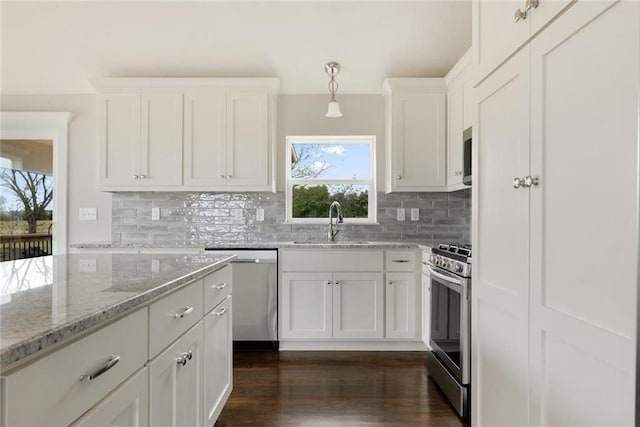 kitchen with sink, appliances with stainless steel finishes, dark hardwood / wood-style floors, decorative light fixtures, and white cabinets