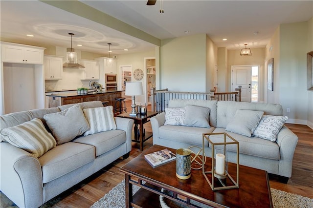 living room with ceiling fan, sink, and dark hardwood / wood-style flooring