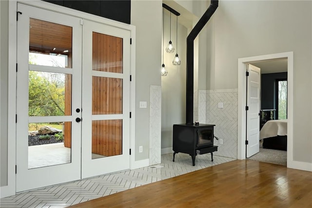 doorway with french doors, light hardwood / wood-style floors, and a wood stove