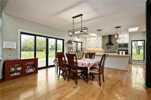 dining area featuring plenty of natural light, light hardwood / wood-style flooring, and a skylight