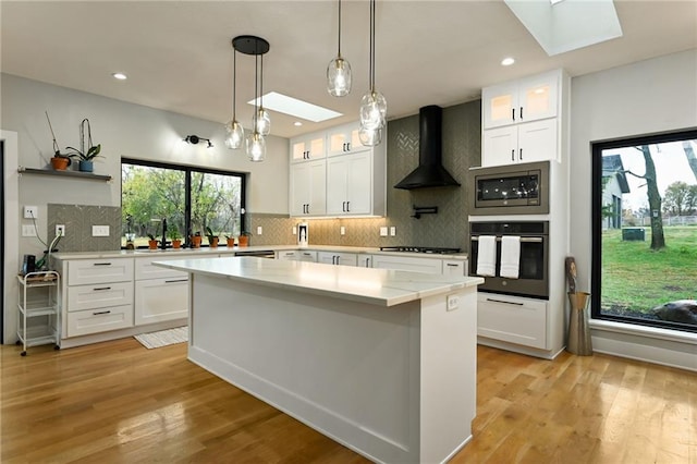 kitchen featuring white cabinetry, stainless steel appliances, and a skylight