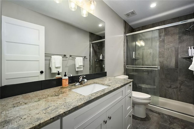 bathroom with a shower with door, vanity, and toilet