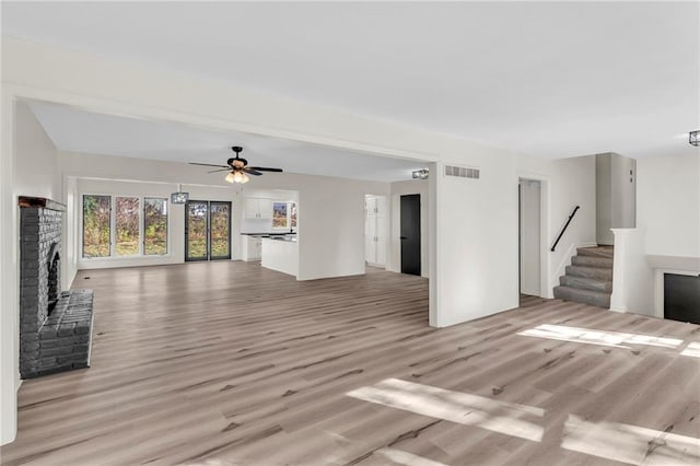 unfurnished living room with ceiling fan, a fireplace, and light hardwood / wood-style floors