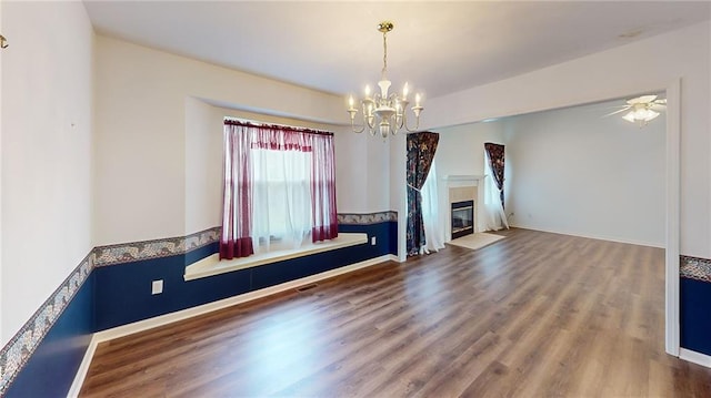 unfurnished living room with ceiling fan with notable chandelier and hardwood / wood-style flooring