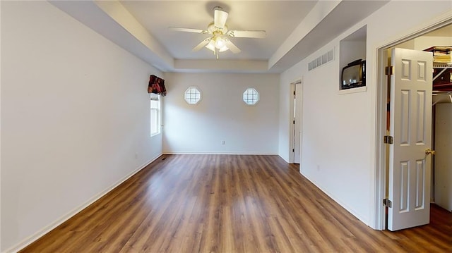 spare room featuring a raised ceiling, ceiling fan, and dark hardwood / wood-style flooring