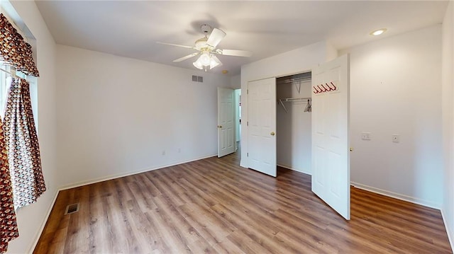 unfurnished bedroom with ceiling fan, wood-type flooring, and a closet