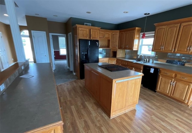 kitchen featuring sink, black appliances, decorative light fixtures, light hardwood / wood-style flooring, and a center island