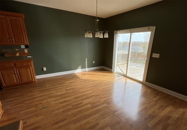 unfurnished dining area featuring hardwood / wood-style flooring and a chandelier