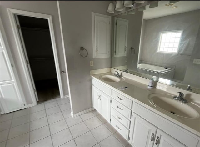 bathroom with a bath, vanity, and tile patterned flooring