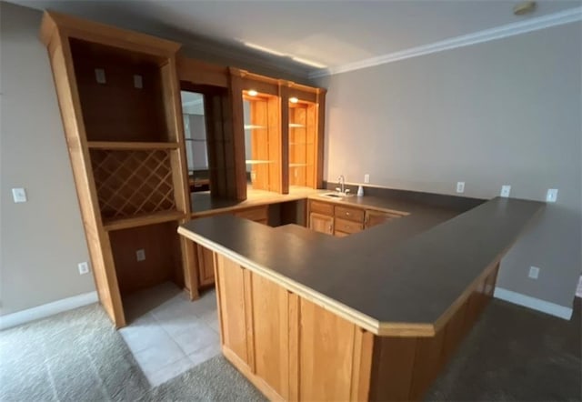 kitchen featuring kitchen peninsula, sink, light colored carpet, and crown molding