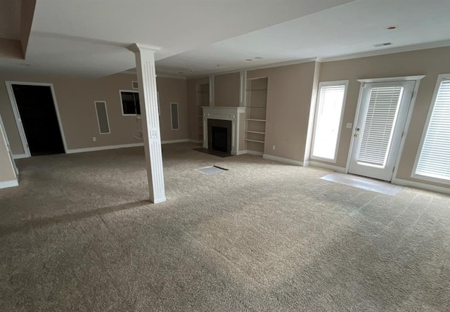 unfurnished living room featuring ornamental molding, decorative columns, a healthy amount of sunlight, and carpet floors