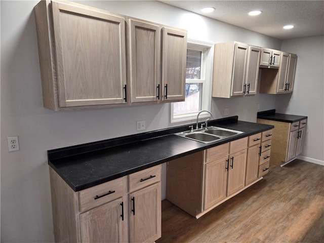 kitchen with hardwood / wood-style flooring, light brown cabinets, sink, and a textured ceiling