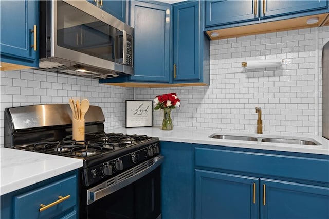 kitchen with stainless steel appliances, blue cabinetry, sink, and backsplash