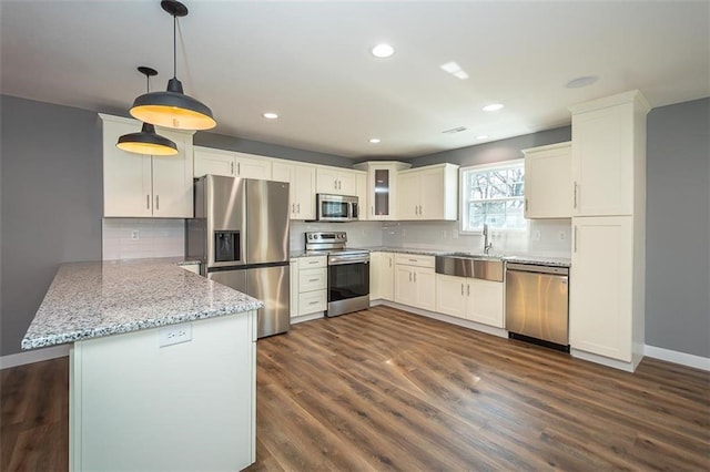 kitchen with stainless steel appliances, sink, decorative light fixtures, dark hardwood / wood-style floors, and white cabinetry