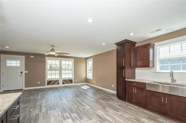 kitchen featuring visible vents, a sink, ceiling fan, light wood-style floors, and a healthy amount of sunlight