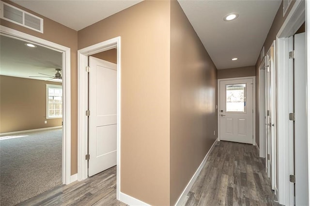 hallway with visible vents, baseboards, recessed lighting, and wood finished floors