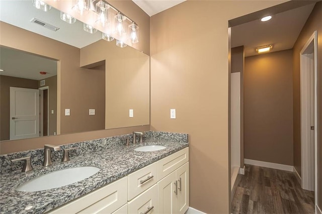 full bathroom with a sink, visible vents, baseboards, and wood finished floors