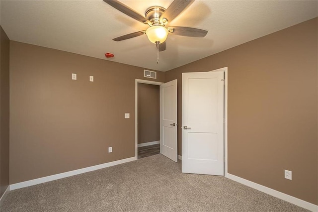 unfurnished bedroom featuring visible vents, light colored carpet, baseboards, and ceiling fan