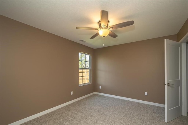 unfurnished room with ceiling fan, a textured ceiling, light colored carpet, visible vents, and baseboards