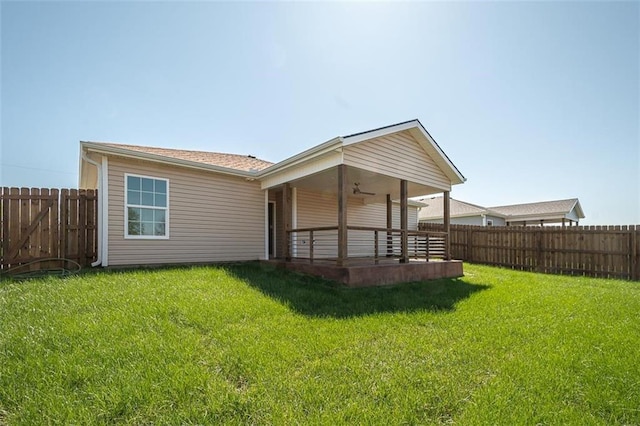 back of property with a yard, a fenced backyard, and a ceiling fan
