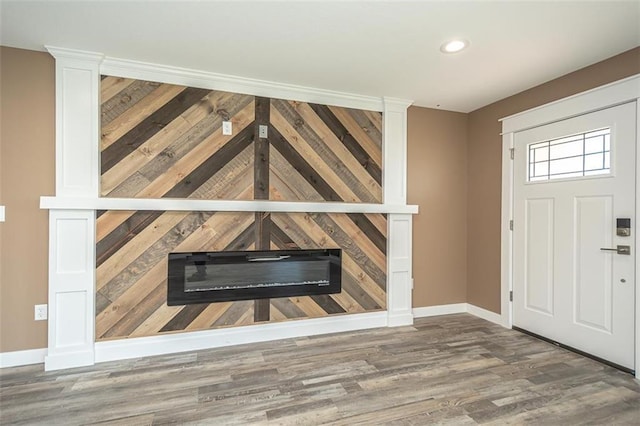 foyer featuring a glass covered fireplace, recessed lighting, baseboards, and wood finished floors