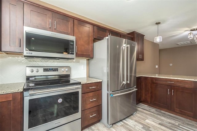 kitchen with light wood-style flooring, backsplash, light stone countertops, visible vents, and stainless steel appliances