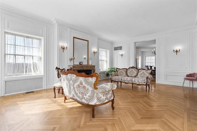 living room with plenty of natural light, radiator heating unit, ornamental molding, and light parquet flooring