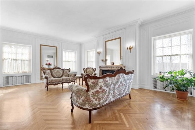 living room featuring a wealth of natural light, ornamental molding, radiator, and light parquet flooring