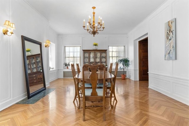 dining area with crown molding, light parquet flooring, and a notable chandelier