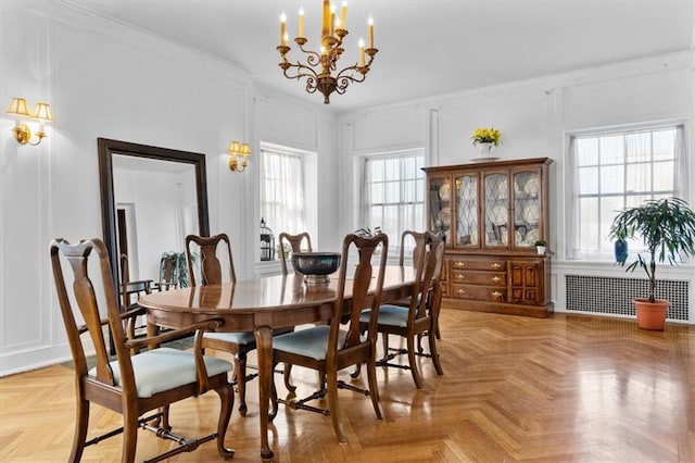 dining area with light parquet flooring, radiator heating unit, a wealth of natural light, and an inviting chandelier