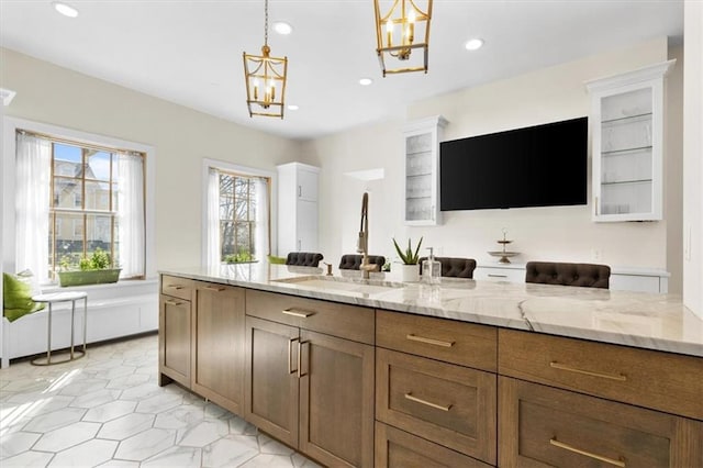 kitchen with a notable chandelier, sink, light stone countertops, and hanging light fixtures