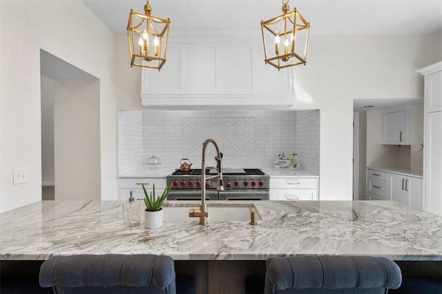 kitchen featuring decorative backsplash, white cabinetry, and decorative light fixtures