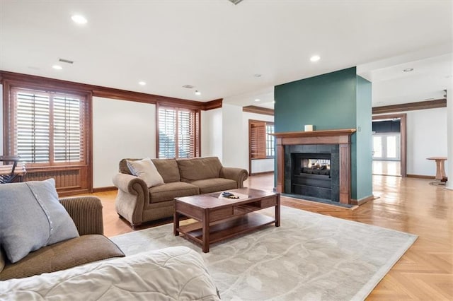 living room featuring light parquet floors, a wealth of natural light, and a tiled fireplace