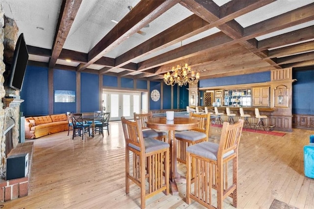 dining area featuring beamed ceiling, a notable chandelier, and light hardwood / wood-style flooring