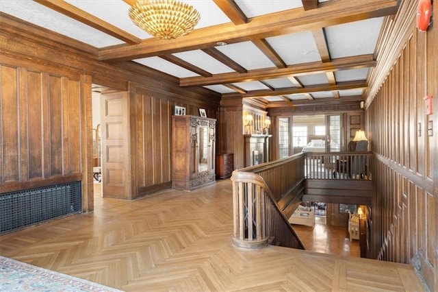 hallway with beam ceiling, wood walls, light parquet flooring, and an inviting chandelier